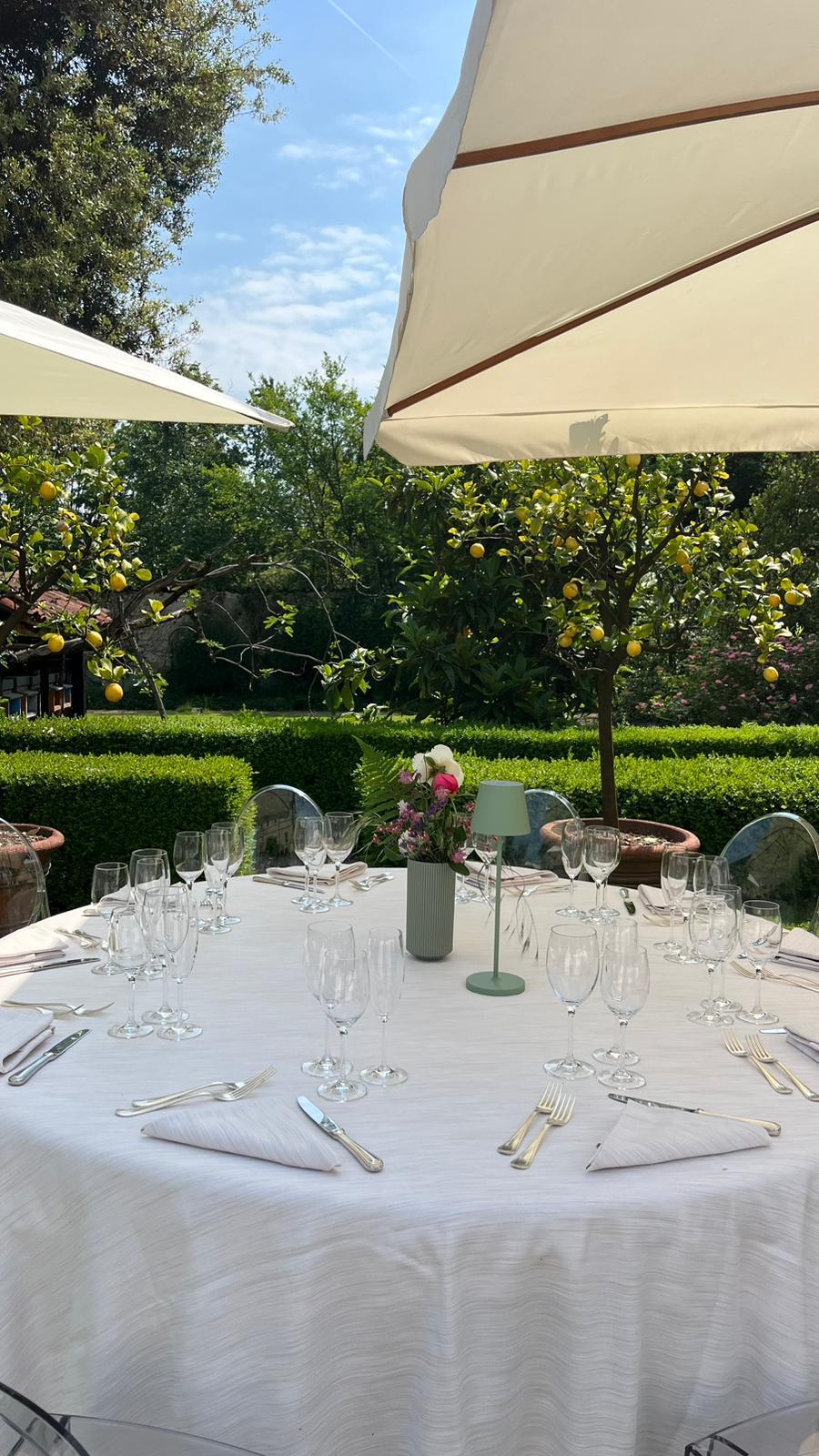 Giardino allestito con tavoli e ombrelloni per ricevimento